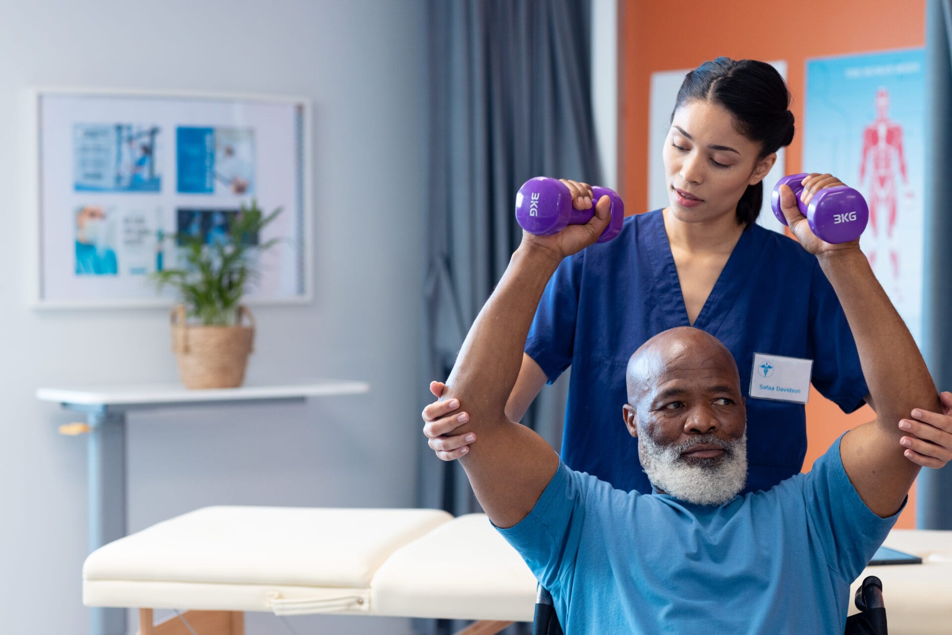 Diverse female physiotherapist helping senior male patient exercise with dumbbells, copy space. Hospital, medical and healthcare services.